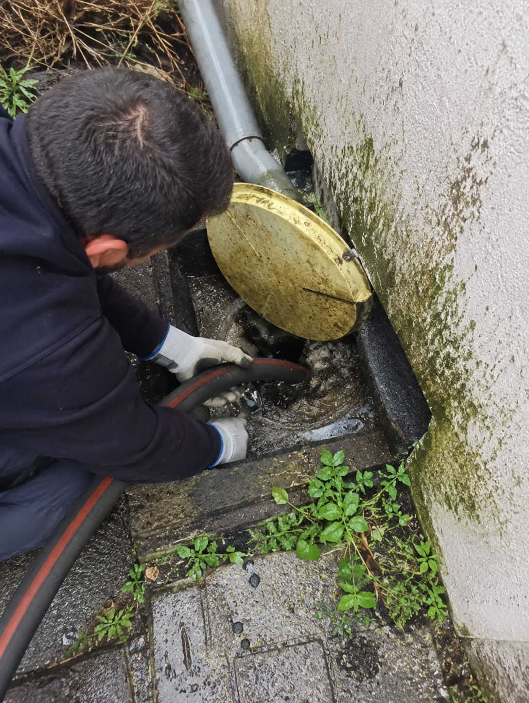 Technicien Azur Services en train de déboucher un regard extérieur avec un flexible haute pression